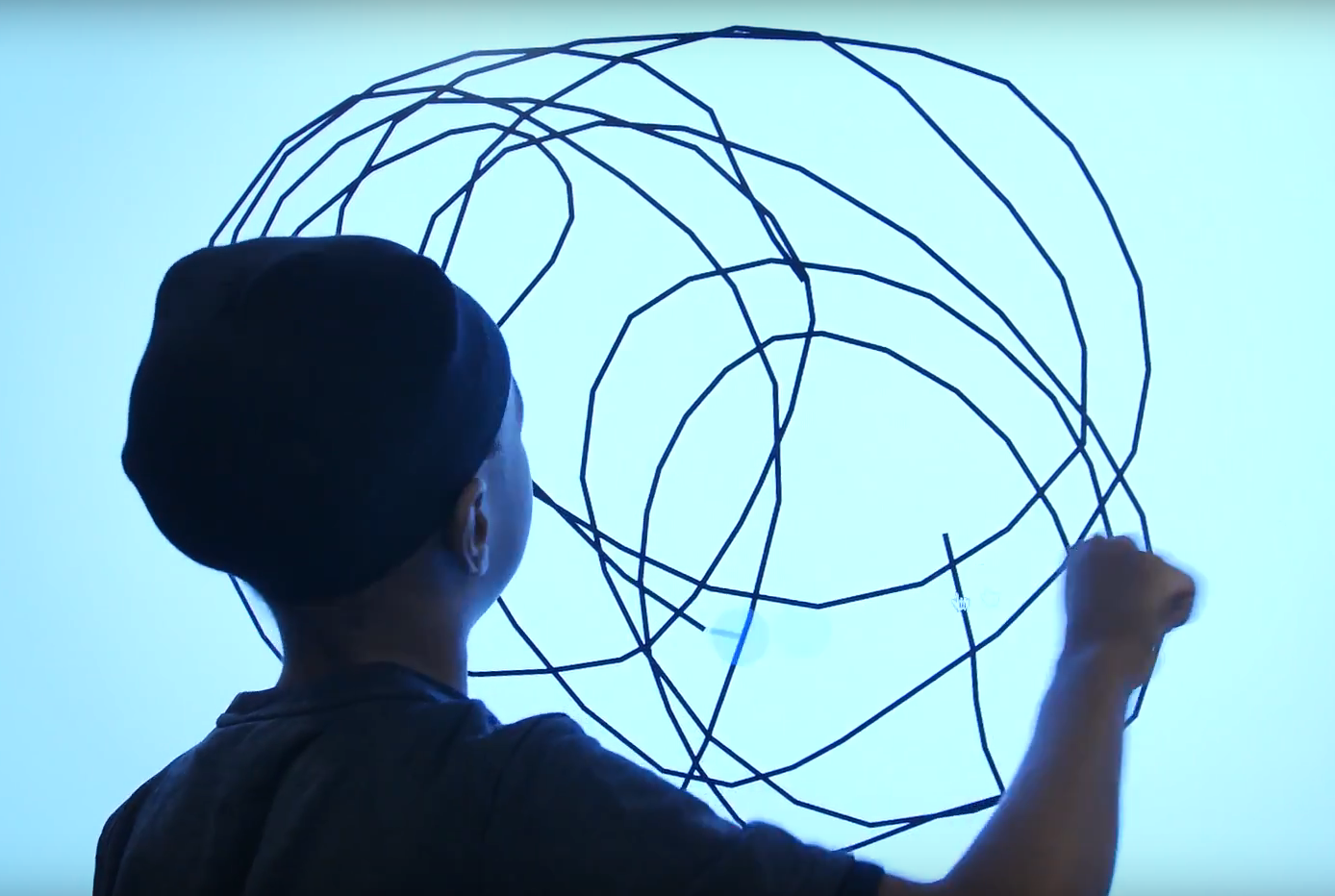 Child drawing black circles on a blue screen.